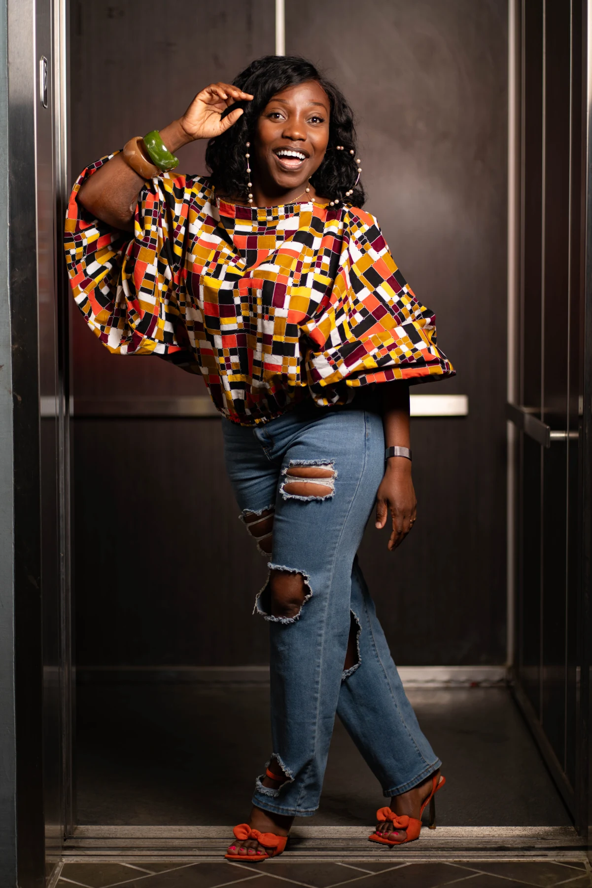 Portrait of a smiling woman in a patterned blouse and jeans.